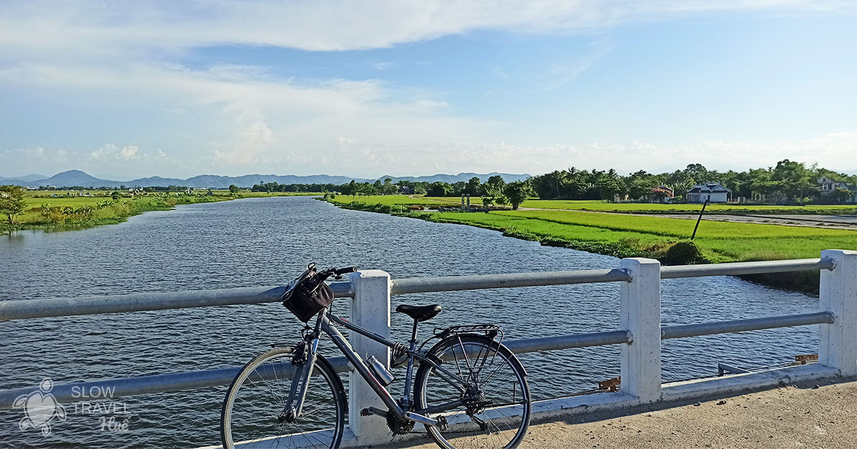 xe đạp bên sông và ruộng lúa